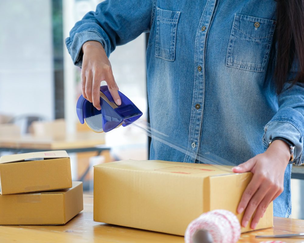 Teenage girls are packing products in boxes and using clear adhesive tape to deliver to customers.